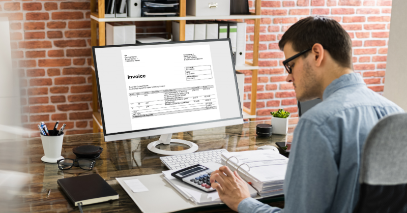 Person working on laptop with an invoice on the screen