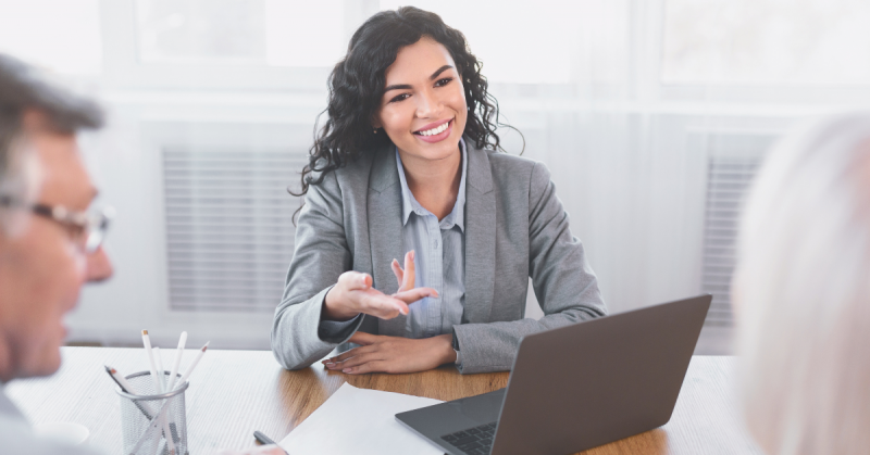 Person sitting at desk speaking with two other people